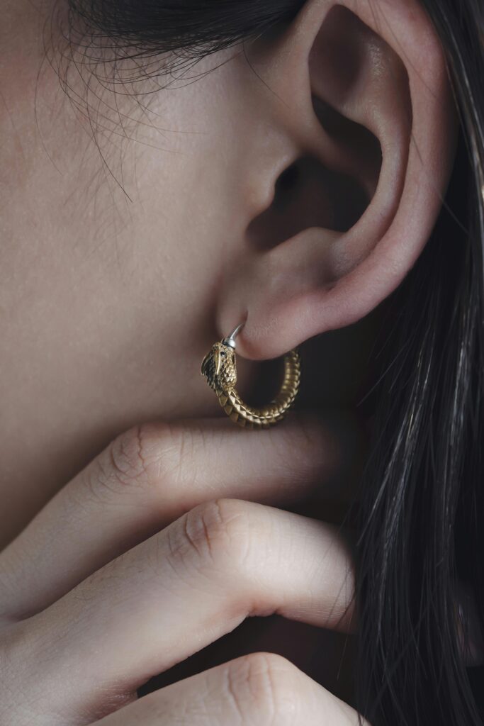 pexels-photo-15785514-15785514 Close-up view of a woman's ear adorned with a delicate gold earring.
