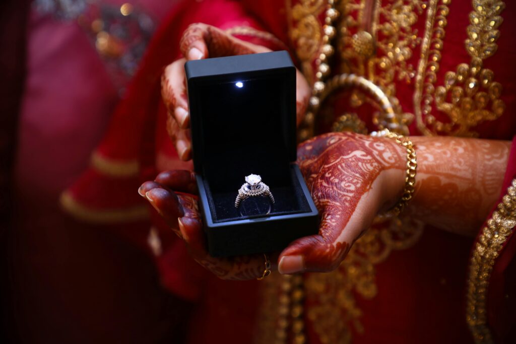 pexels-photo-3871582-3871582 Elegant diamond ring in luxurious box held by hands with intricate henna designs.